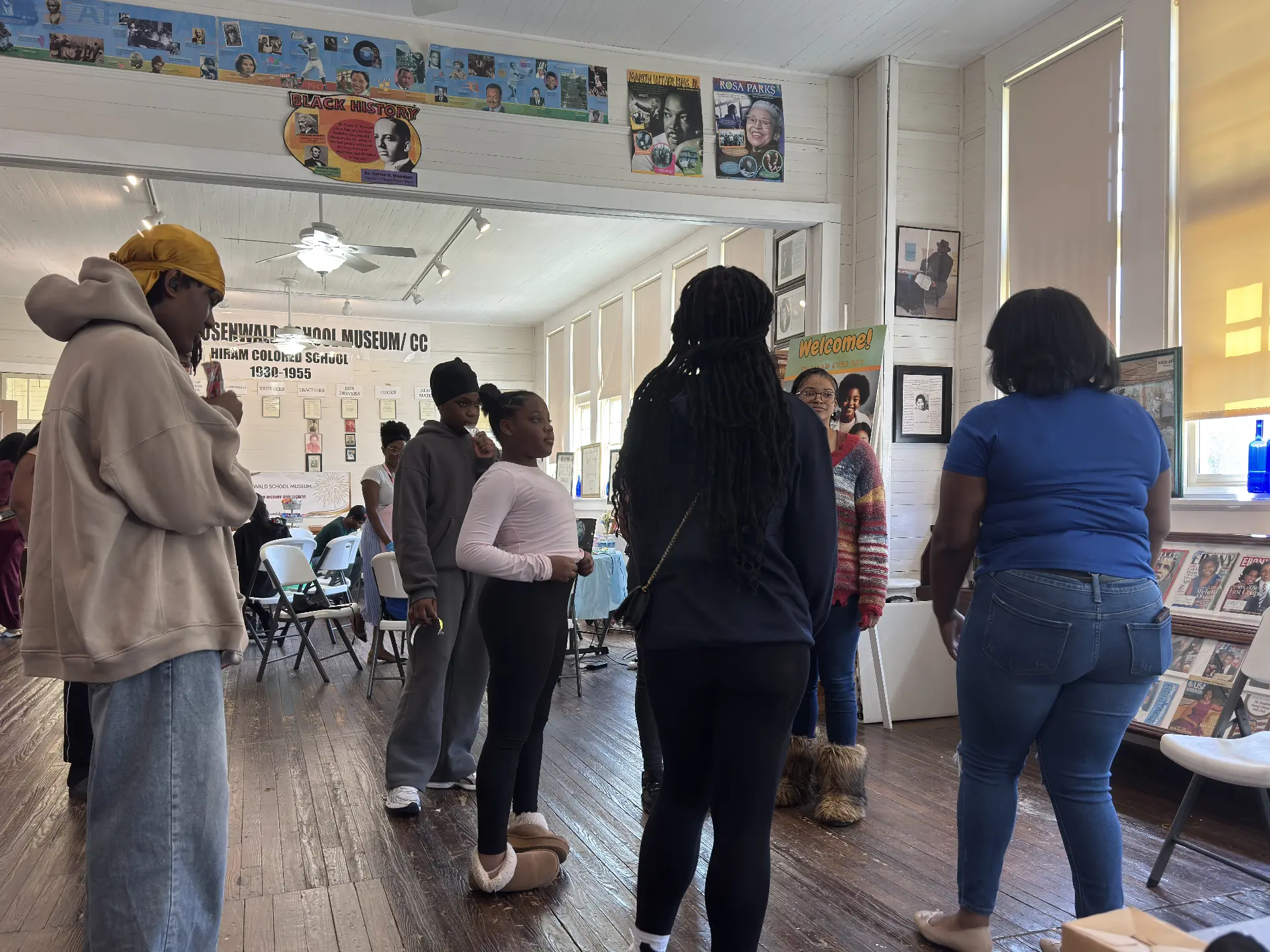 Students gather in a circle inside the museum for a group activity beneath Black history posters.