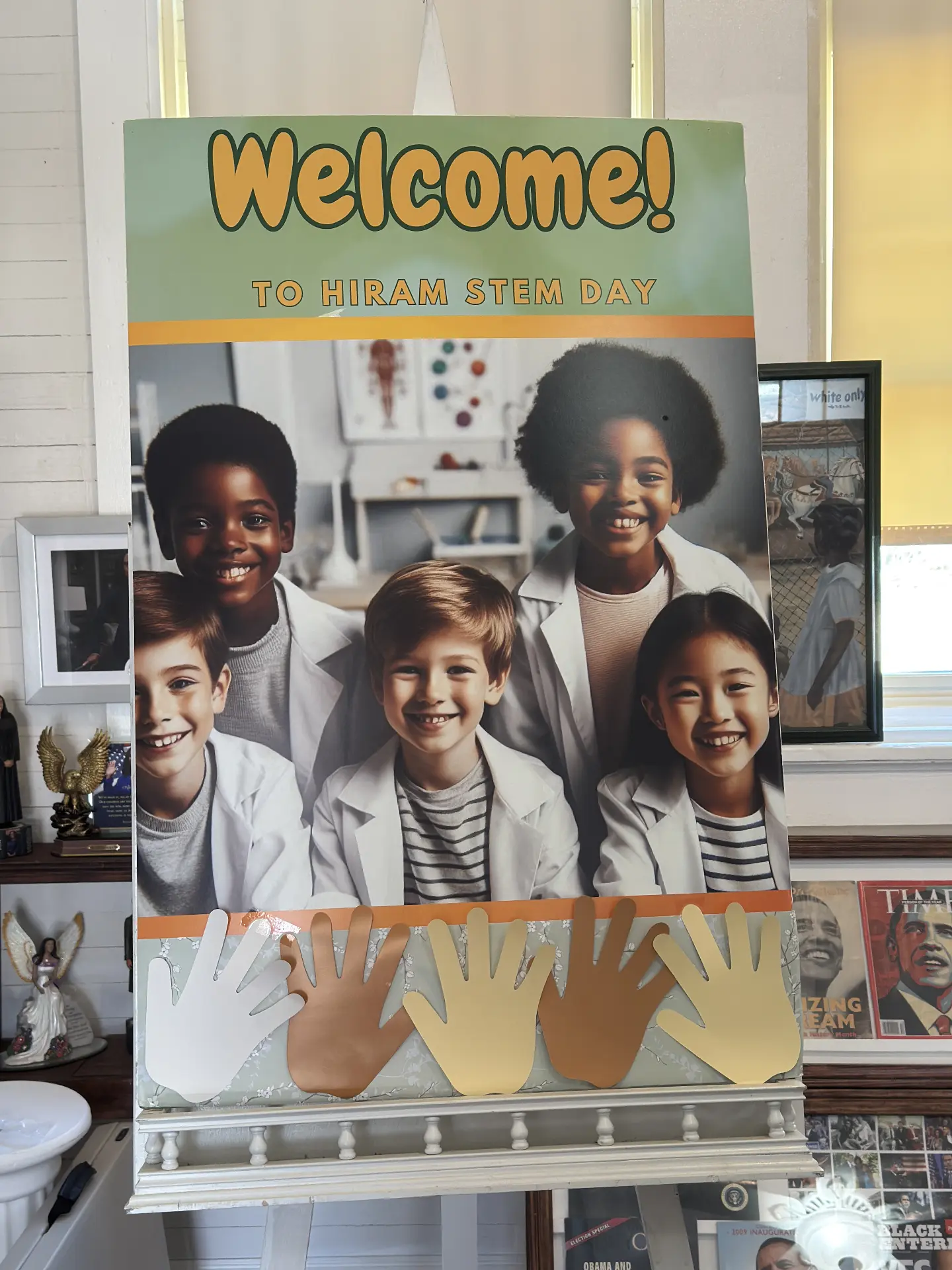 A "Welcome to Hiram STEM Day" sign with smiling young scientists on an easel in the museum.