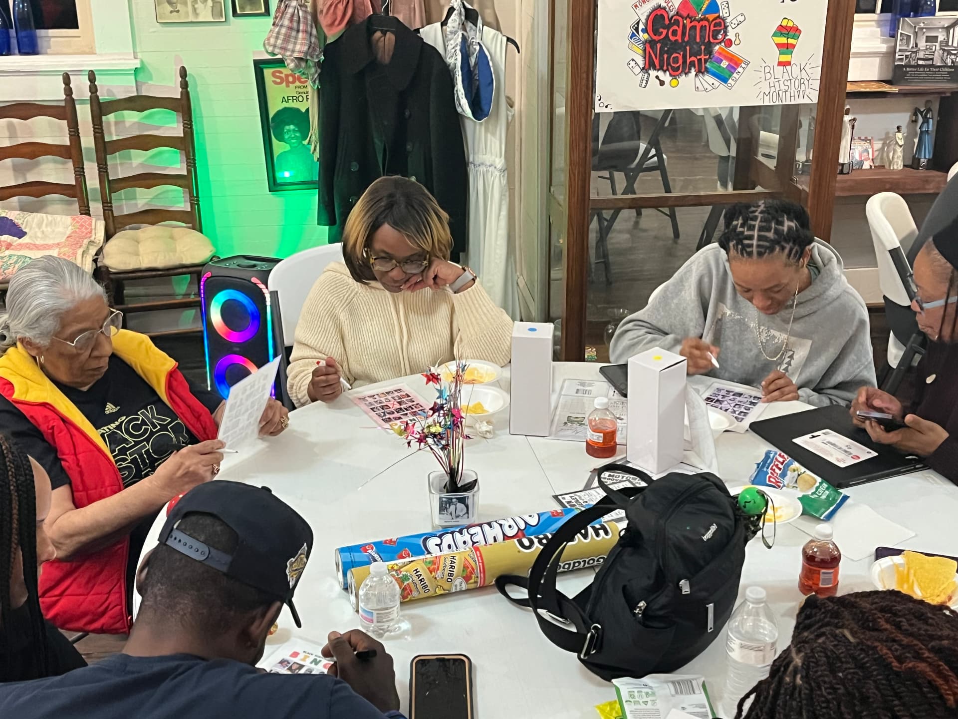 Guests of all ages mark their bingo cards around a table beneath the Game Night sign during Black History Month.