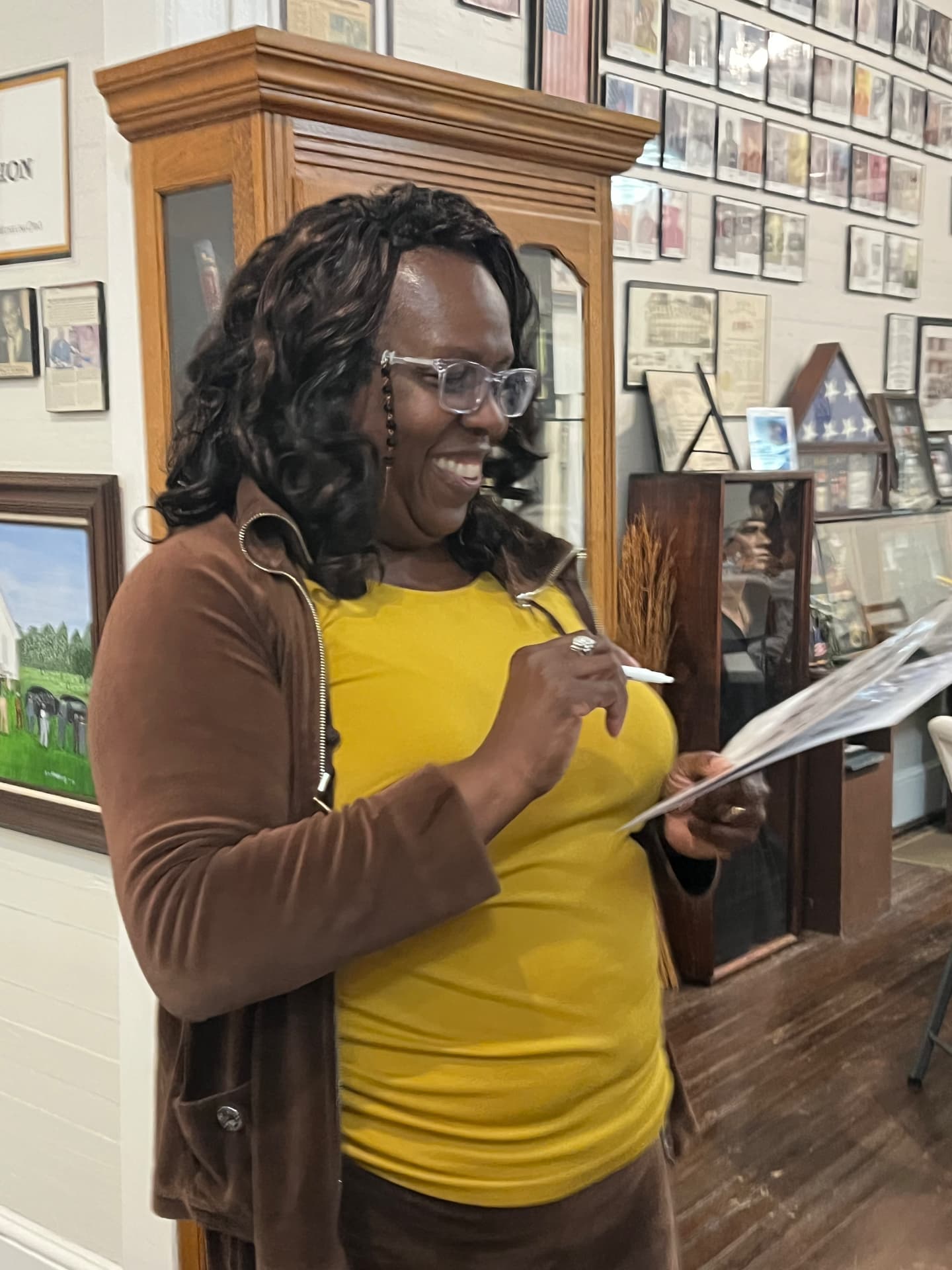 A guest smiles while filling out a Black History Medley bingo card beside the museum's portrait wall.