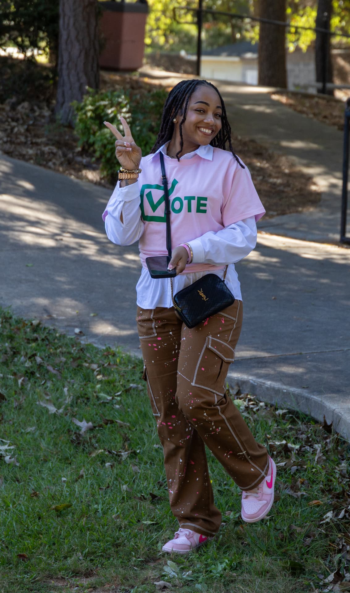 A young woman in a pink VOTE t-shirt flashes a peace sign on the walkway at the block party.