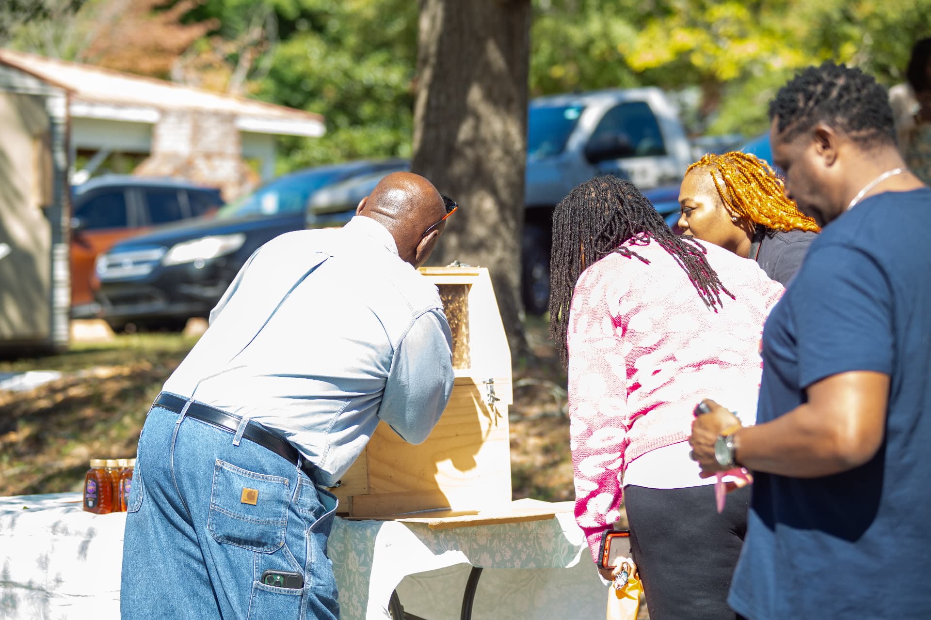Visitors lean in to inspect the observation beehive on display outside during STEM Day.