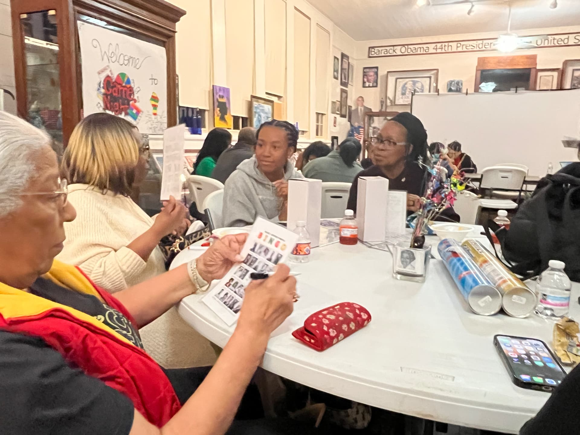 A guest reviews her bingo card near the Welcome to Game Night sign with museum exhibits in the background.