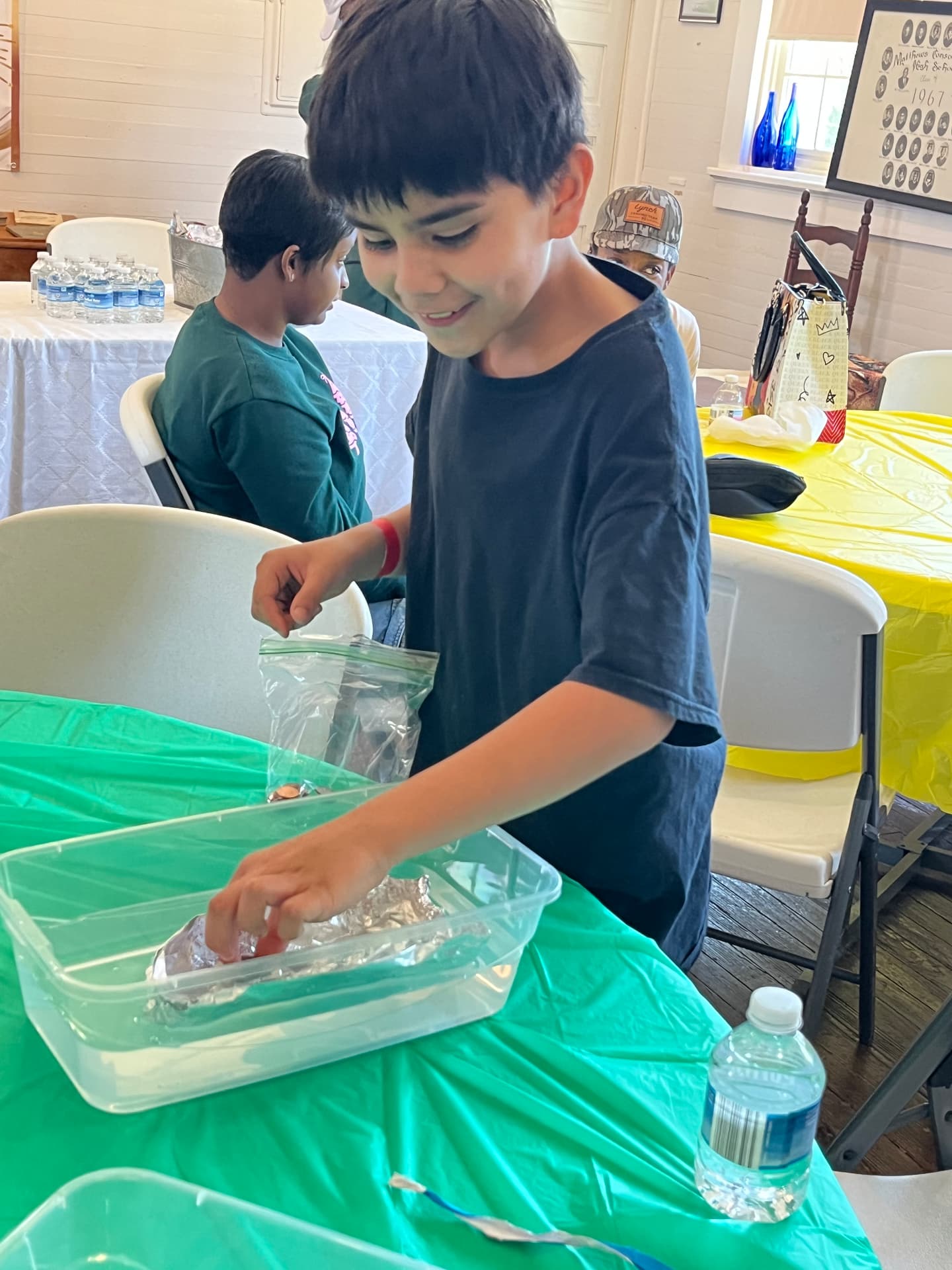 A student carefully places his foil boat into a bin of water during the STEM Day boat-building challenge.