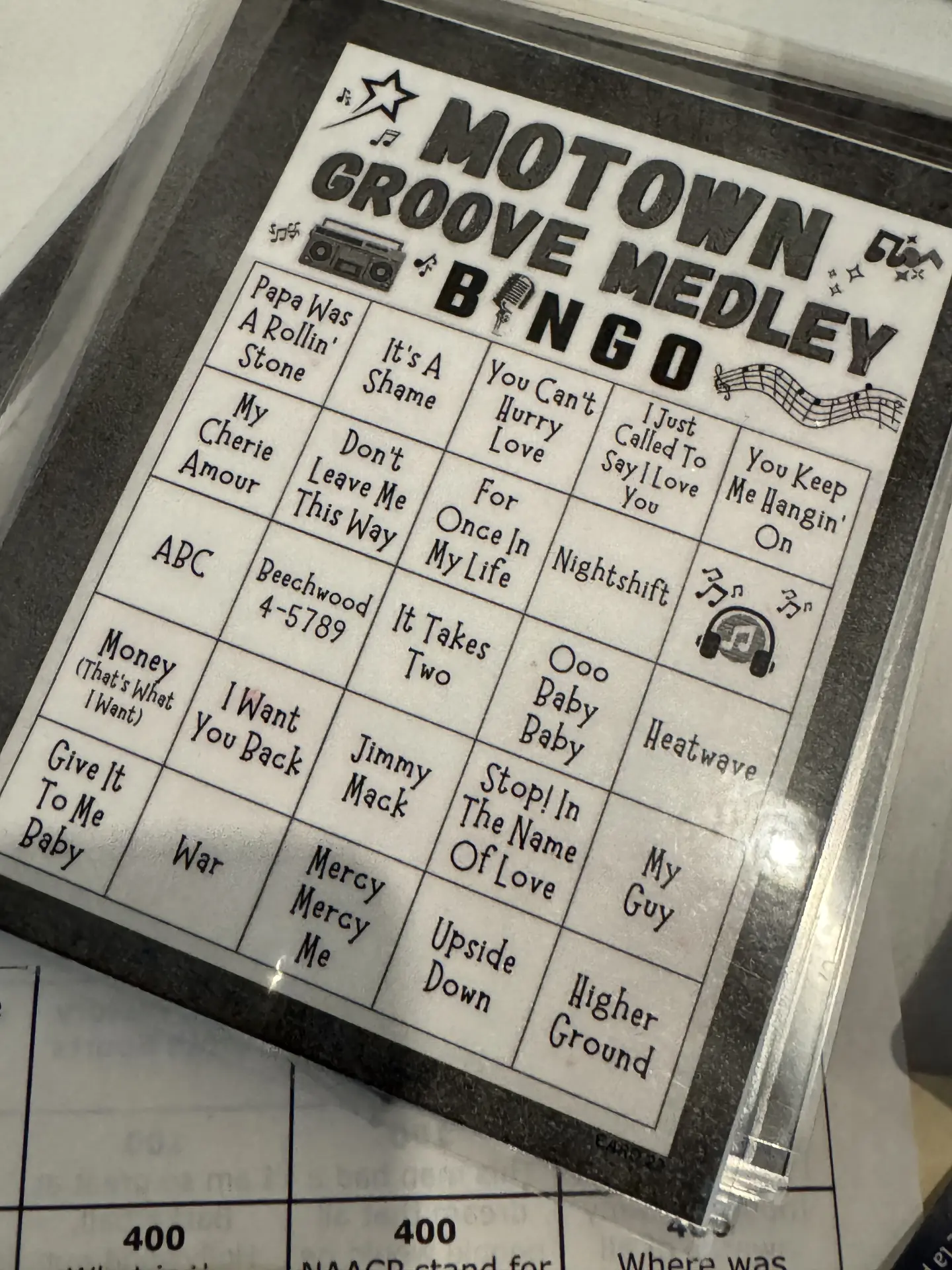 A close-up of a Motown Groove Medley Bingo card featuring classic song titles like My Cherie Amour and War.