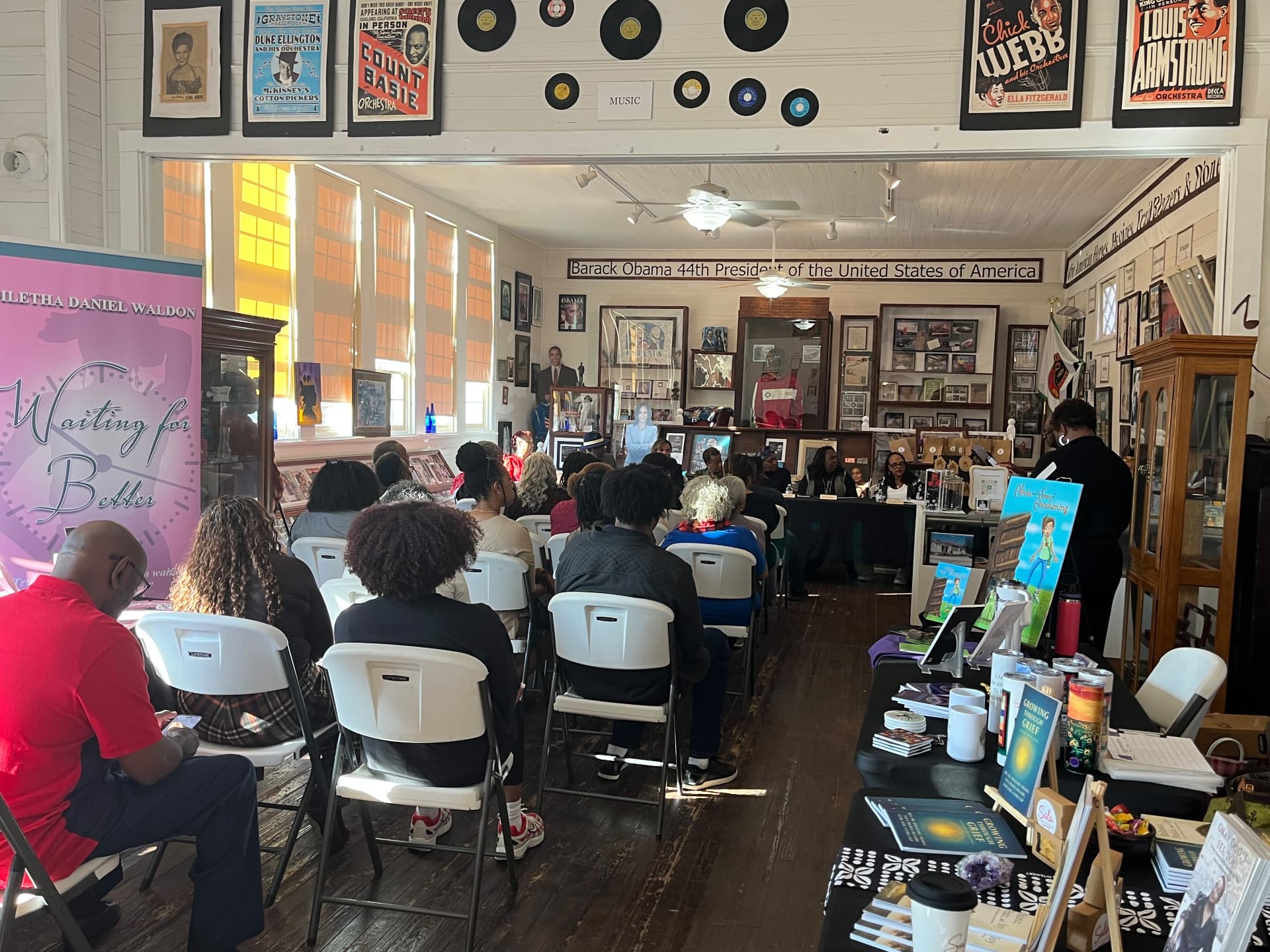 A full room of visitors listens as the author panel speaks beneath the museum's music posters and record collection.