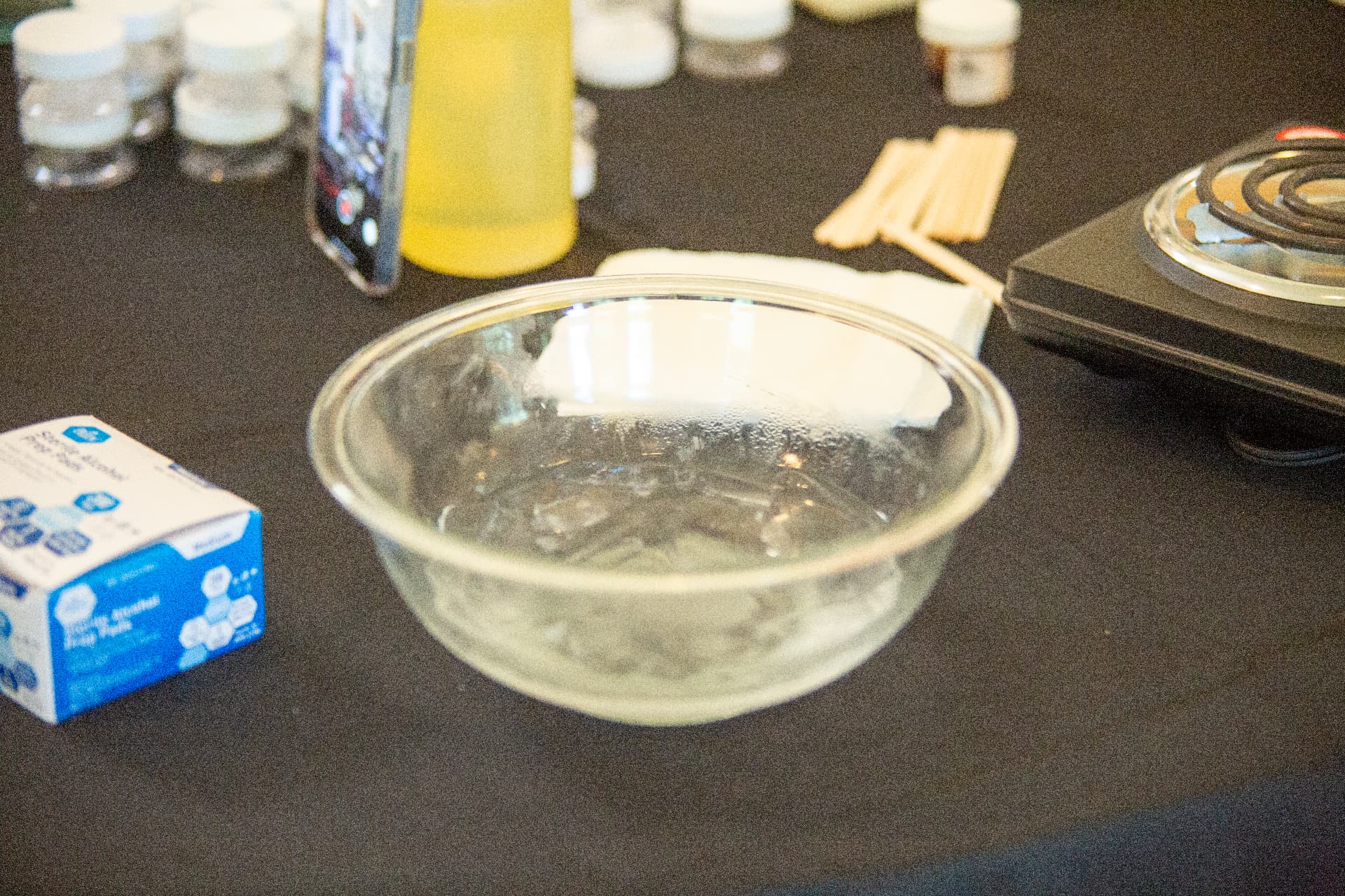Close-up of a glass mixing bowl, measuring scale and lab supplies on a table during a STEM Day experiment.