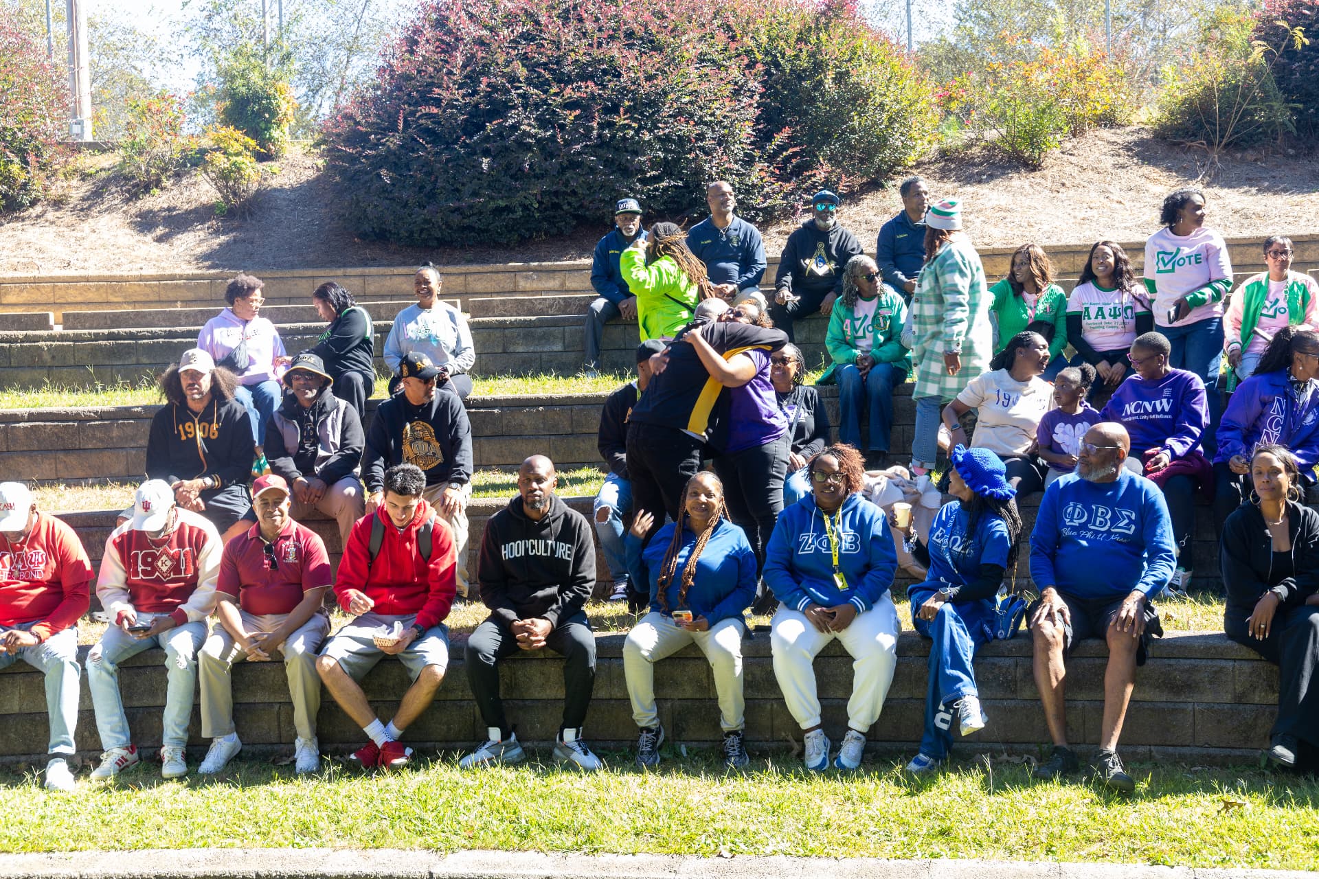 A large group of fraternity and sorority members in their colors gathered on the amphitheater steps for a group photo.