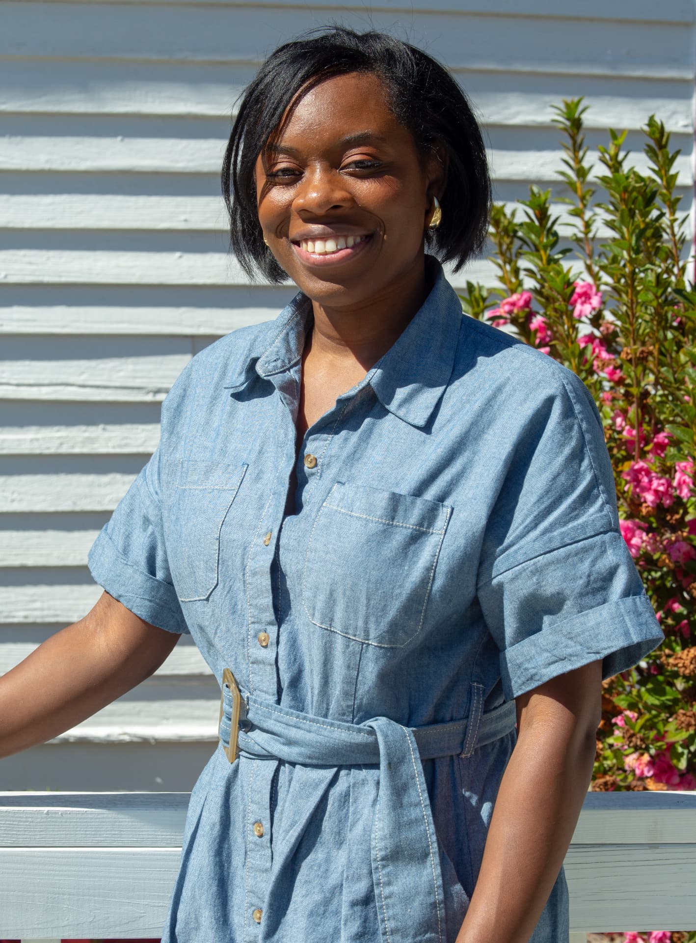 Portrait of a smiling STEM Day host in a denim dress outside the schoolhouse.