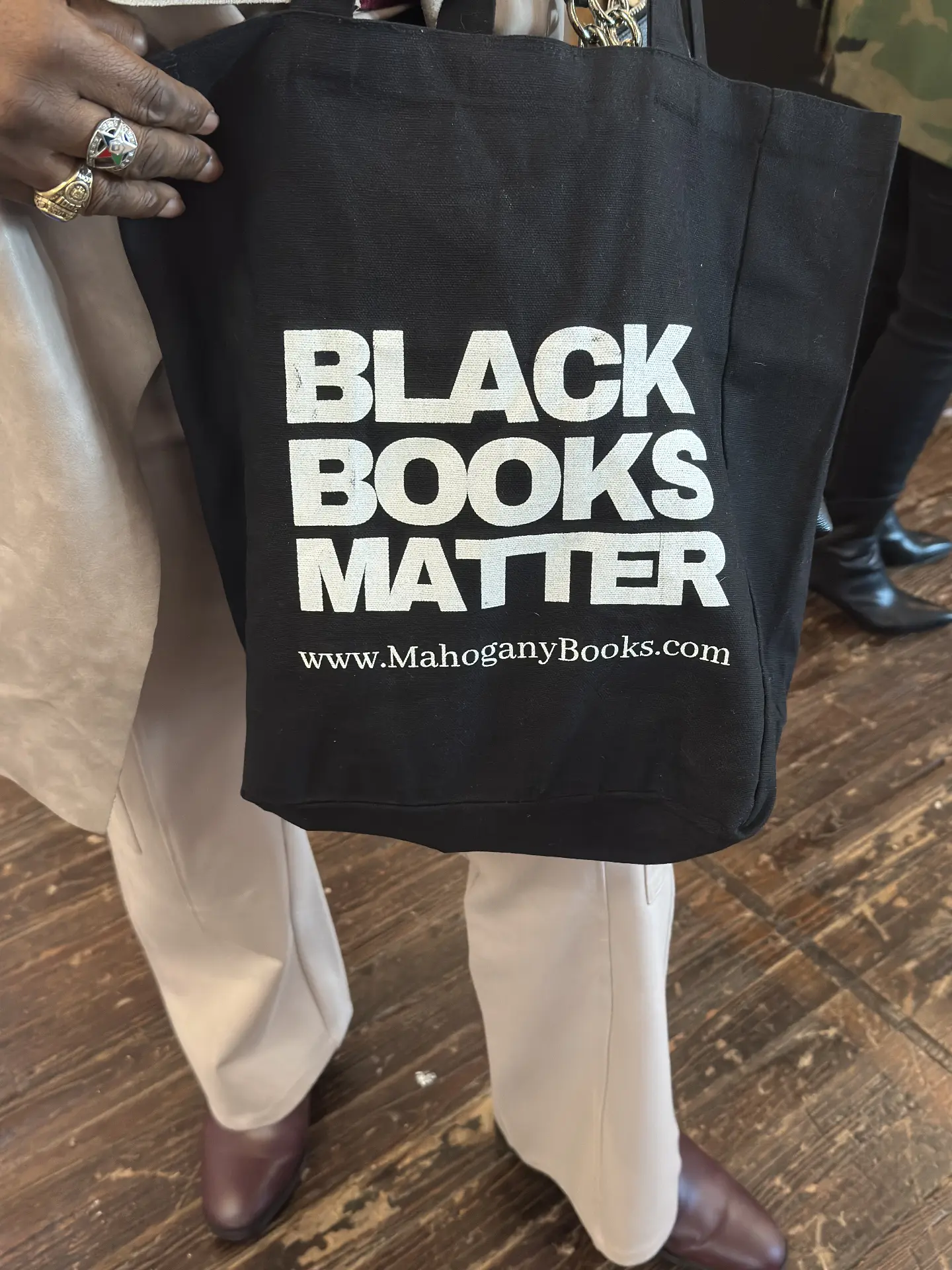 A visitor carries a black tote bag reading Black Books Matter from MahoganyBooks.