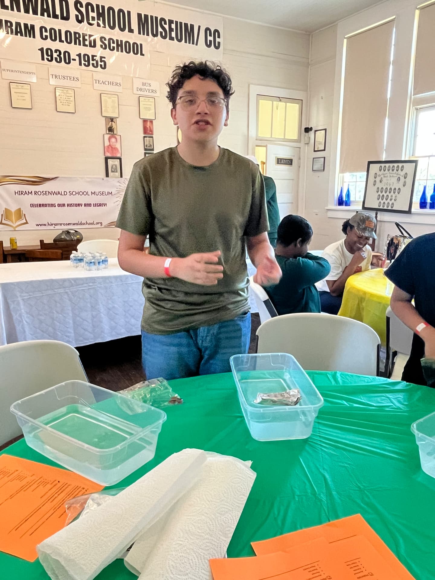 A student leader presents the foil-boat challenge instructions to a table of participants at STEM Day.