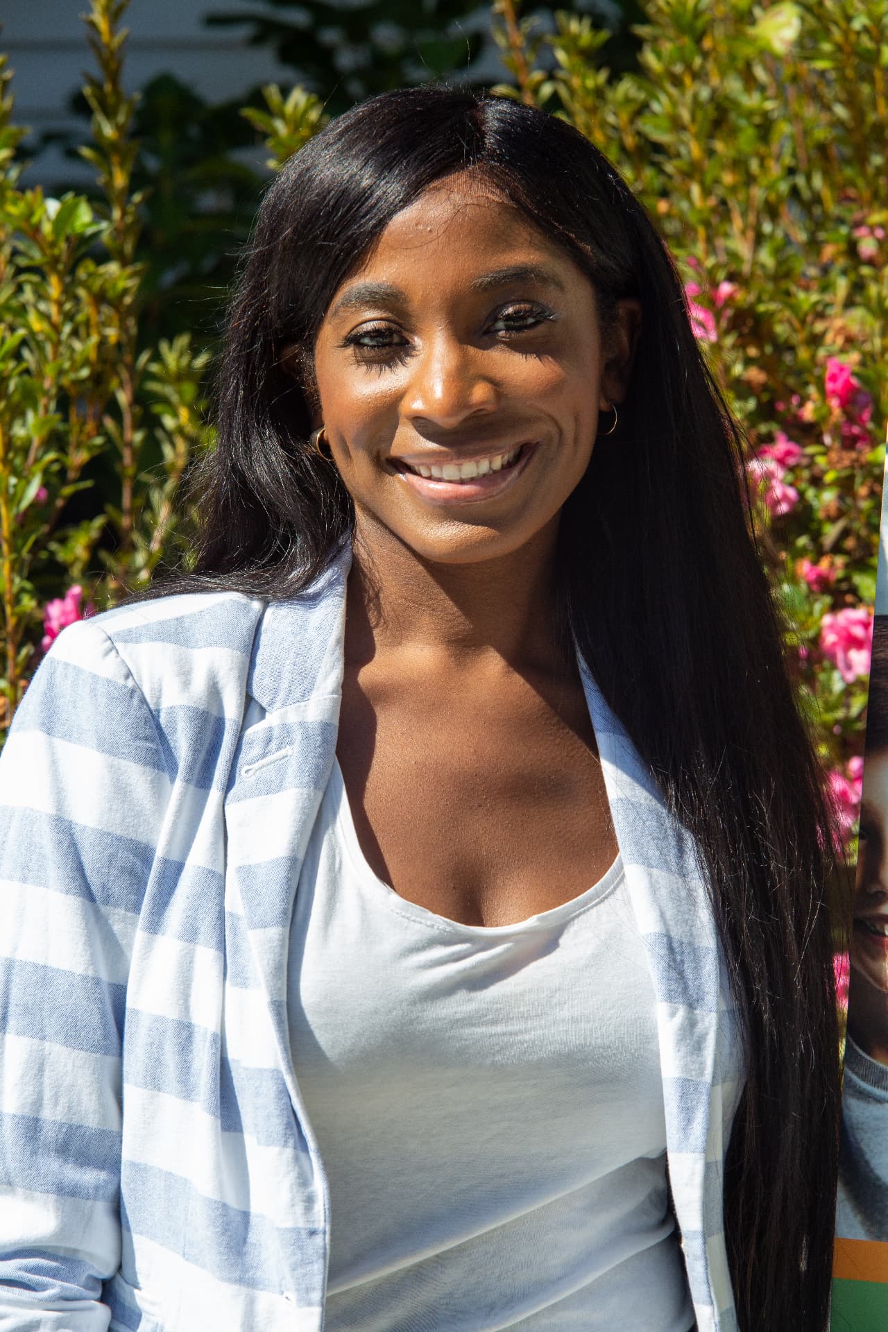 Portrait of a smiling STEM Day host in a striped blazer among pink flowers.