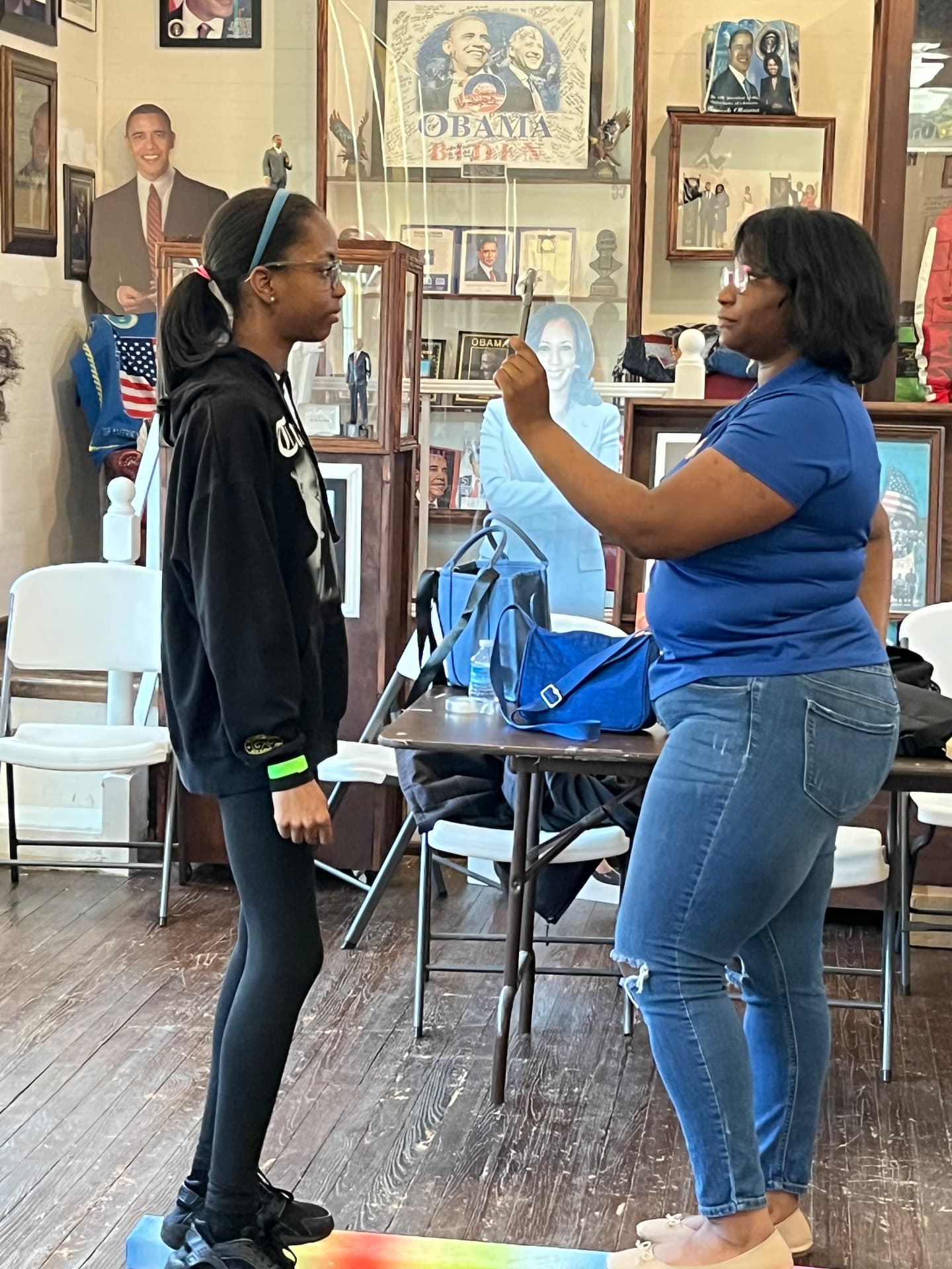 An instructor and a student measure height with a yardstick during a STEM Day activity in the museum.