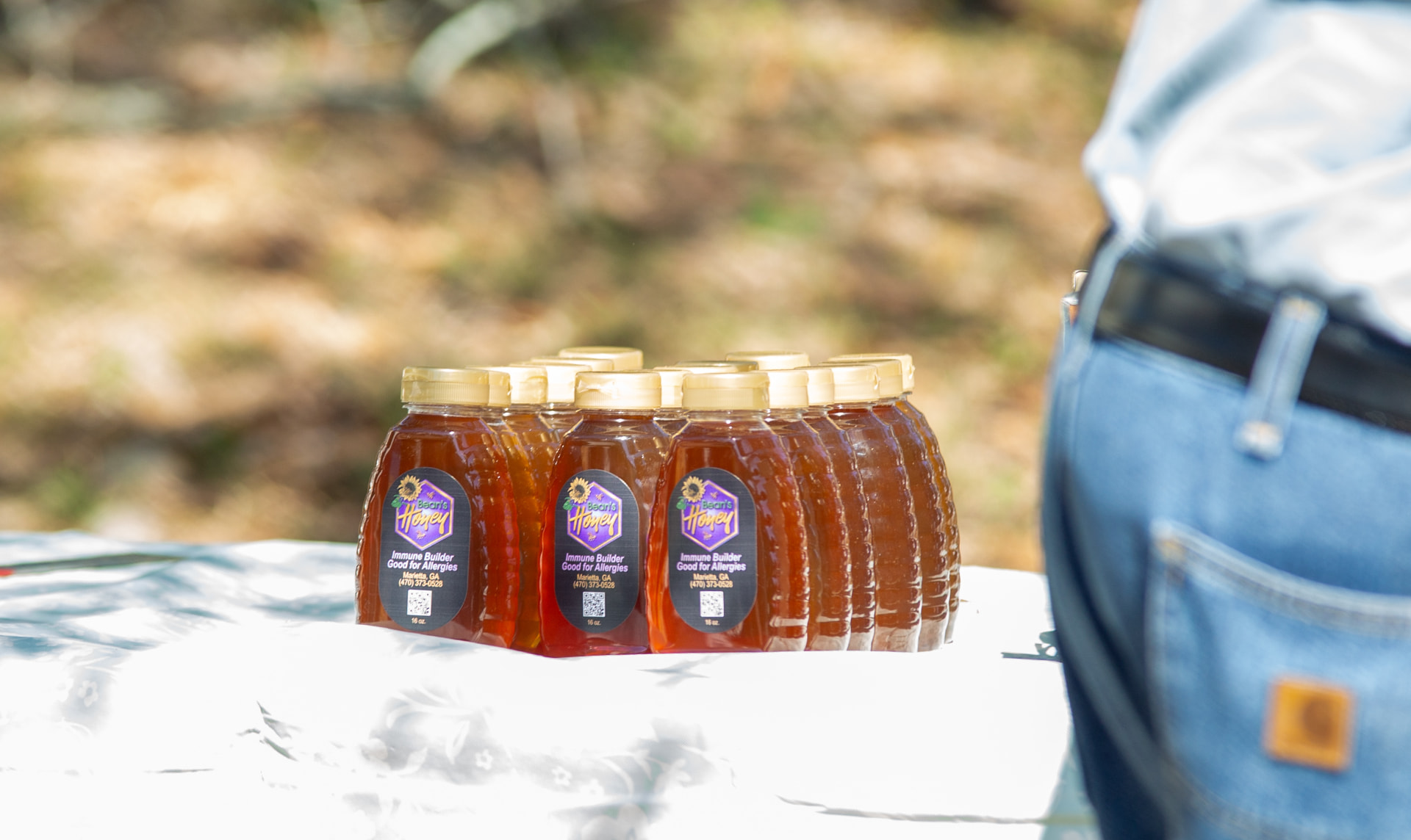 Bottles of local honey with purple labels arranged on a white tablecloth during STEM Day.