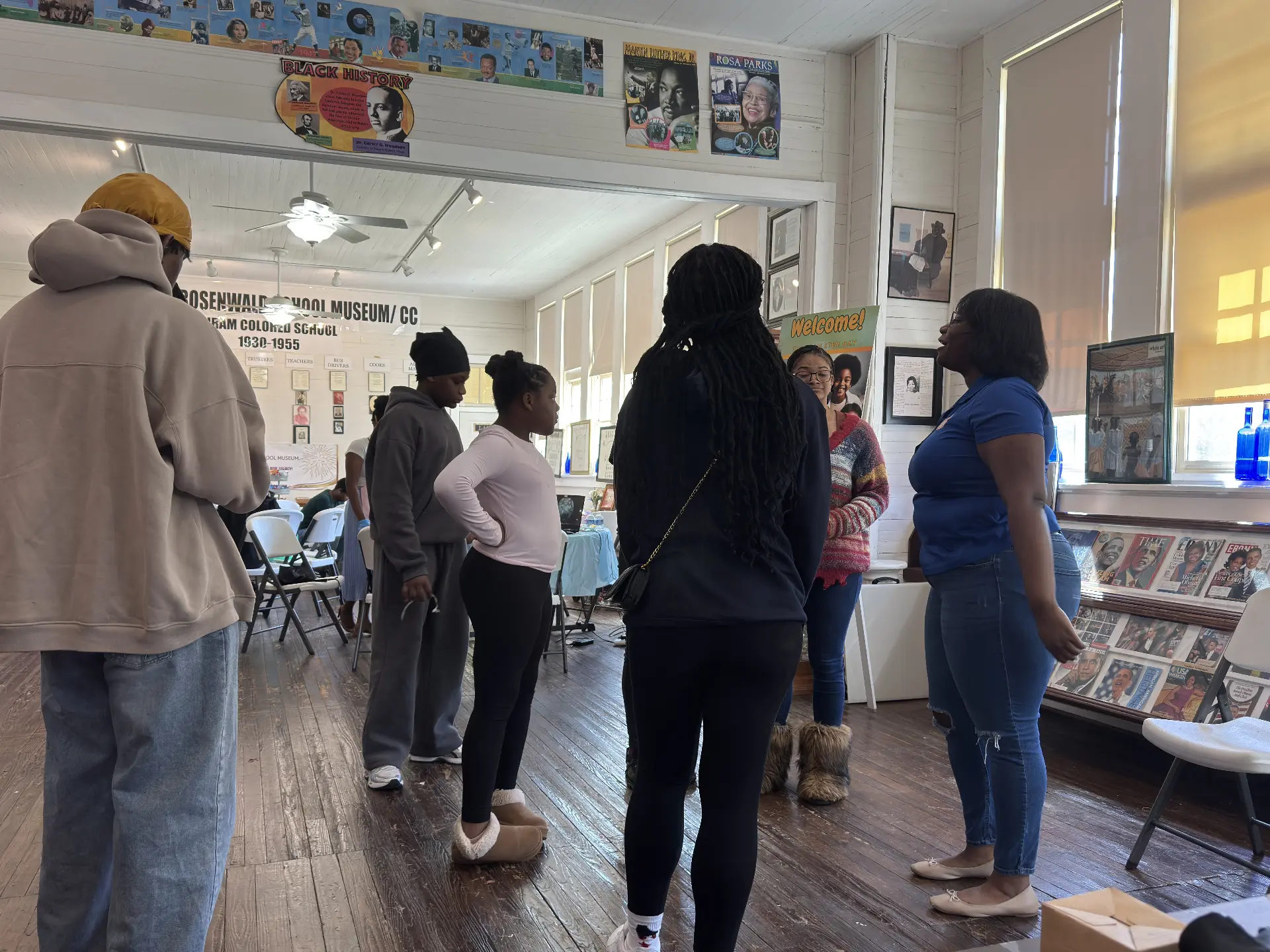 An instructor in blue leads students in a circle activity in the museum during STEM Day.