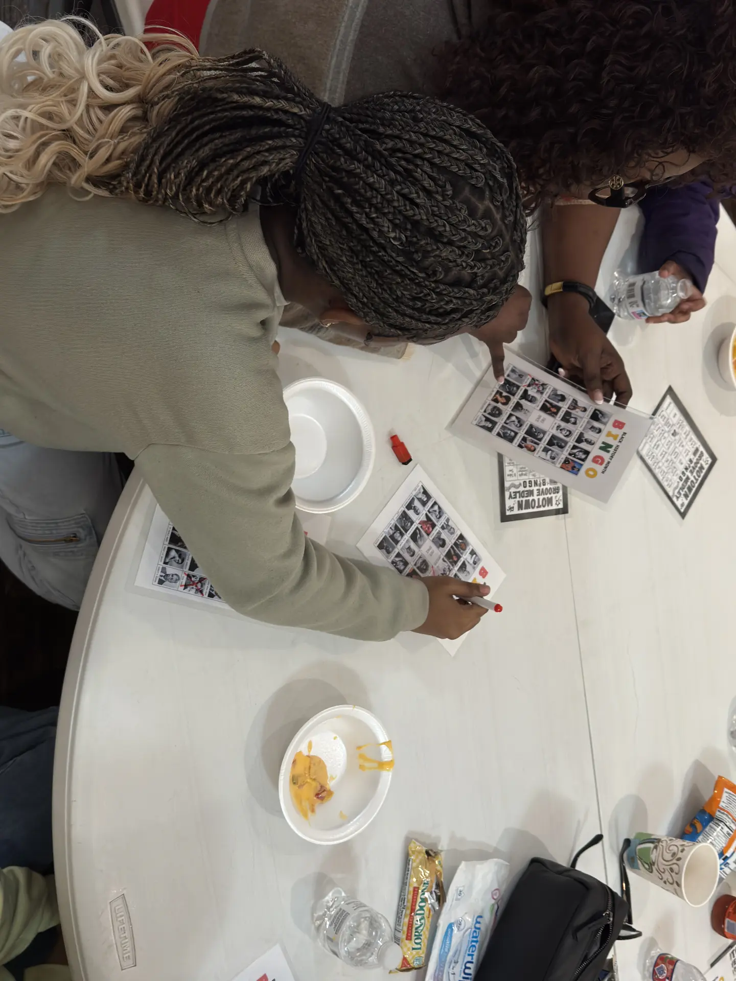 A guest in a green sweater marks her Motown Groove Medley bingo card during Black History Game Night.