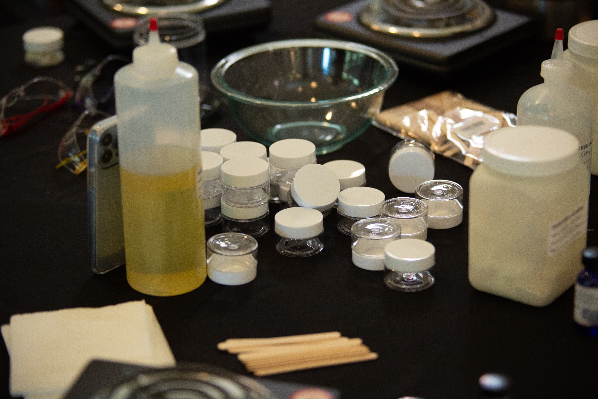 A table of lab supplies including squeeze bottles, small jars, a mixing bowl and wooden stirrers set up for a STEM Day activity.