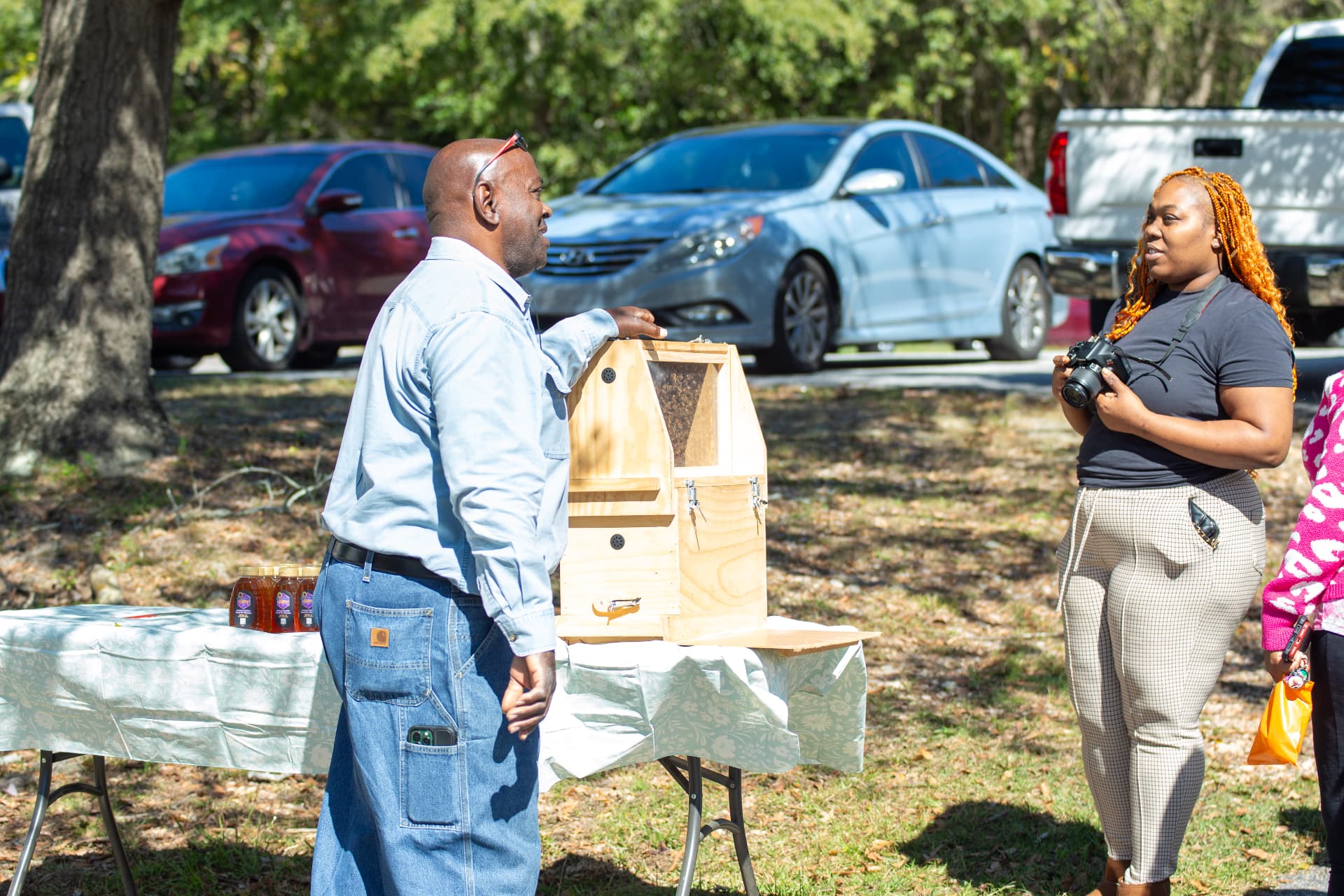 A beekeeper talks about the observation hive with a visitor holding a camera during STEM Day.