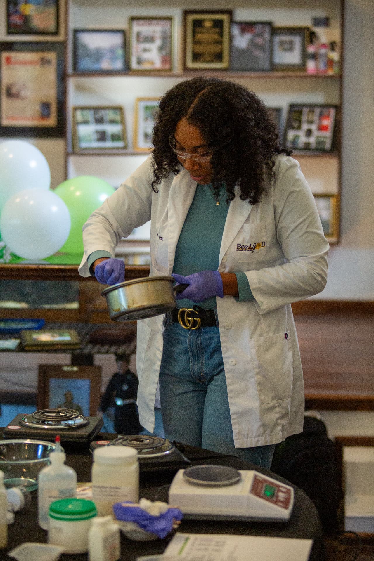 A scientist in a white lab coat pours ingredients from a saucepan during a hands-on STEM experiment at the museum.