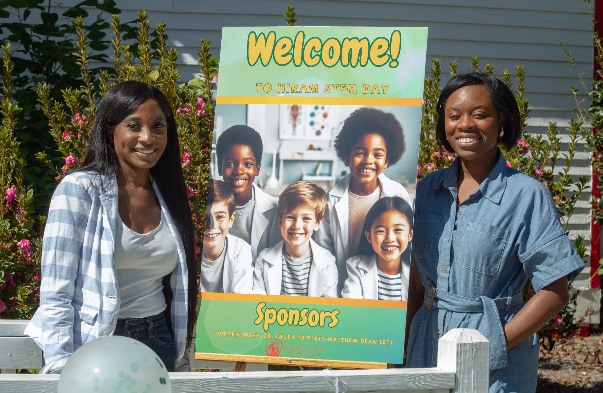 Two STEM Day hosts stand on either side of the Welcome to Hiram STEM Day sign.