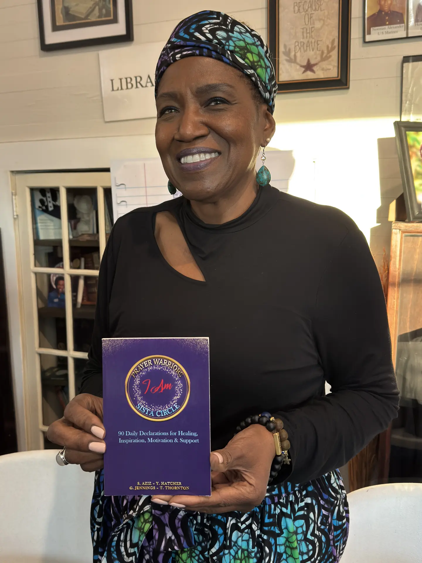 A smiling author in a patterned headwrap holds the Prayer Warriors I Am Sista Circle daily declarations book.